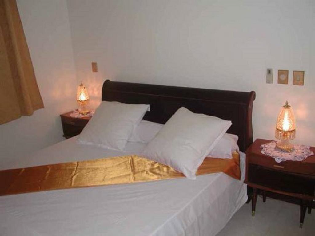 Chambre avec lit double, linge blanc et chemin de lit doré à la Villa Palatium Martinique